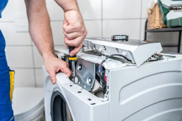 Technician servicing an open washing machine control assembly